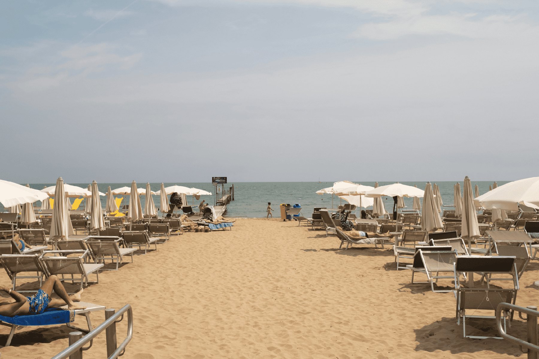 Vista dall'alto di uno stabilimento balneare organizzato: righe di ombrelloni e lettini in pattern simmetrici